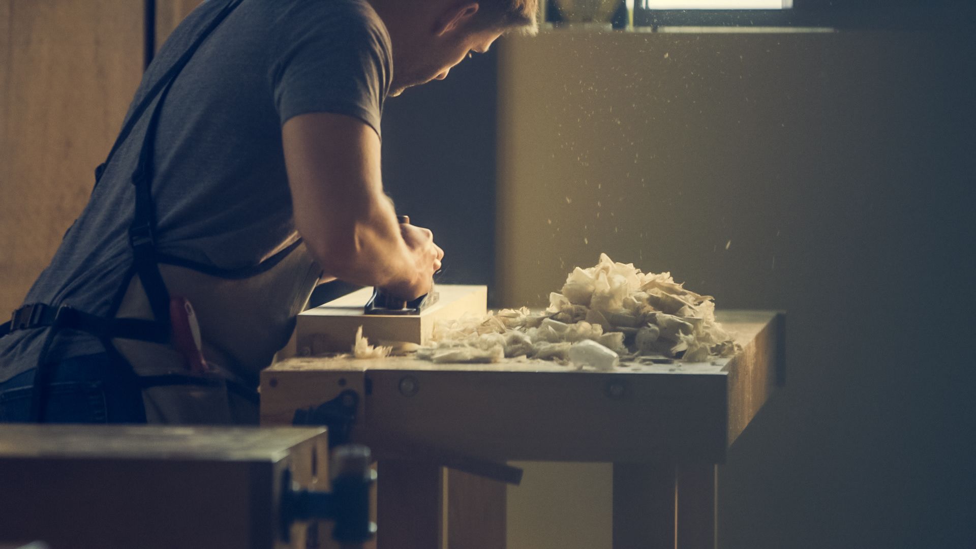 Tischler hobelt ein Brett in der Werkstatt