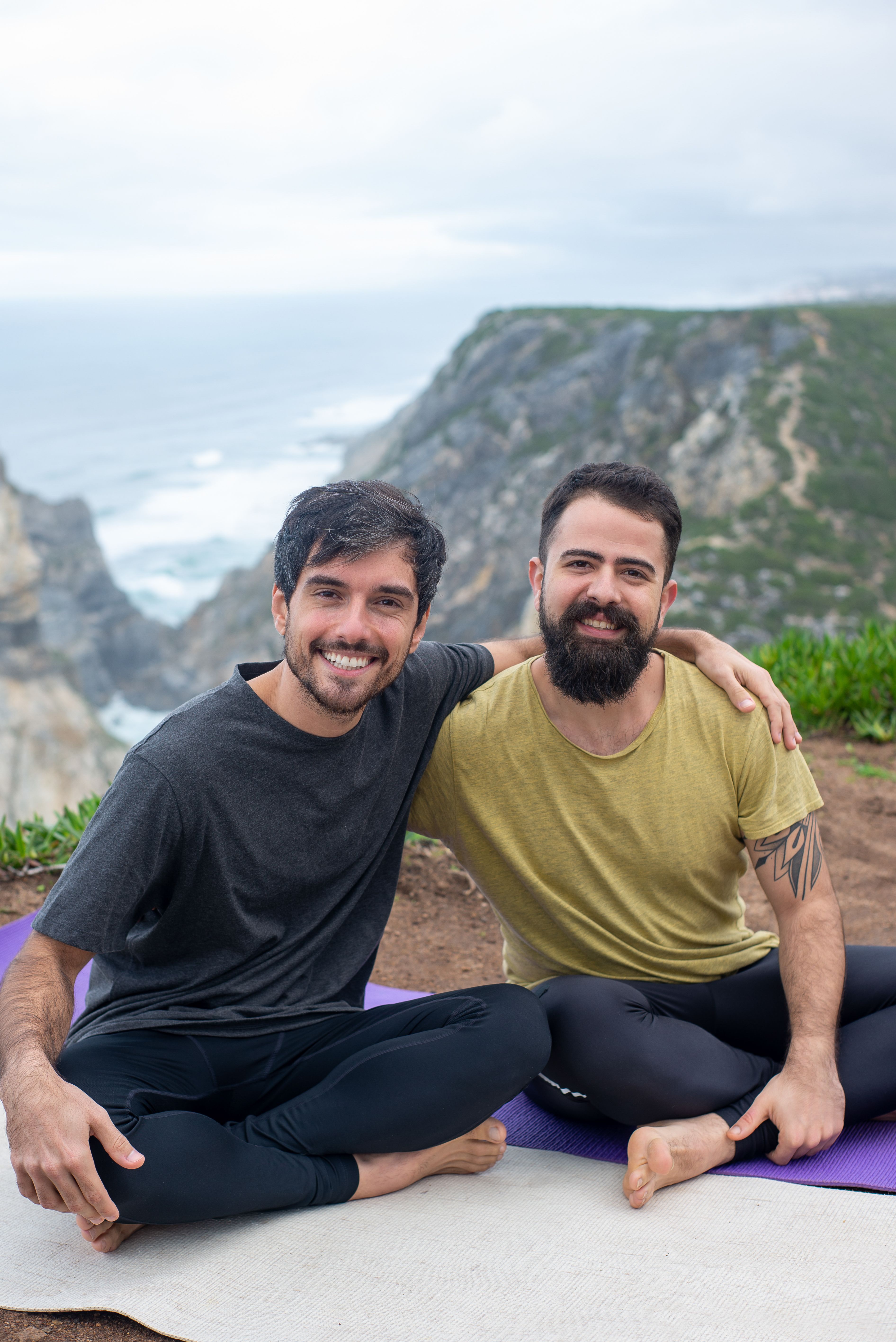 Zwei Menschen beim Yoga auf der Klippe über dem Meer