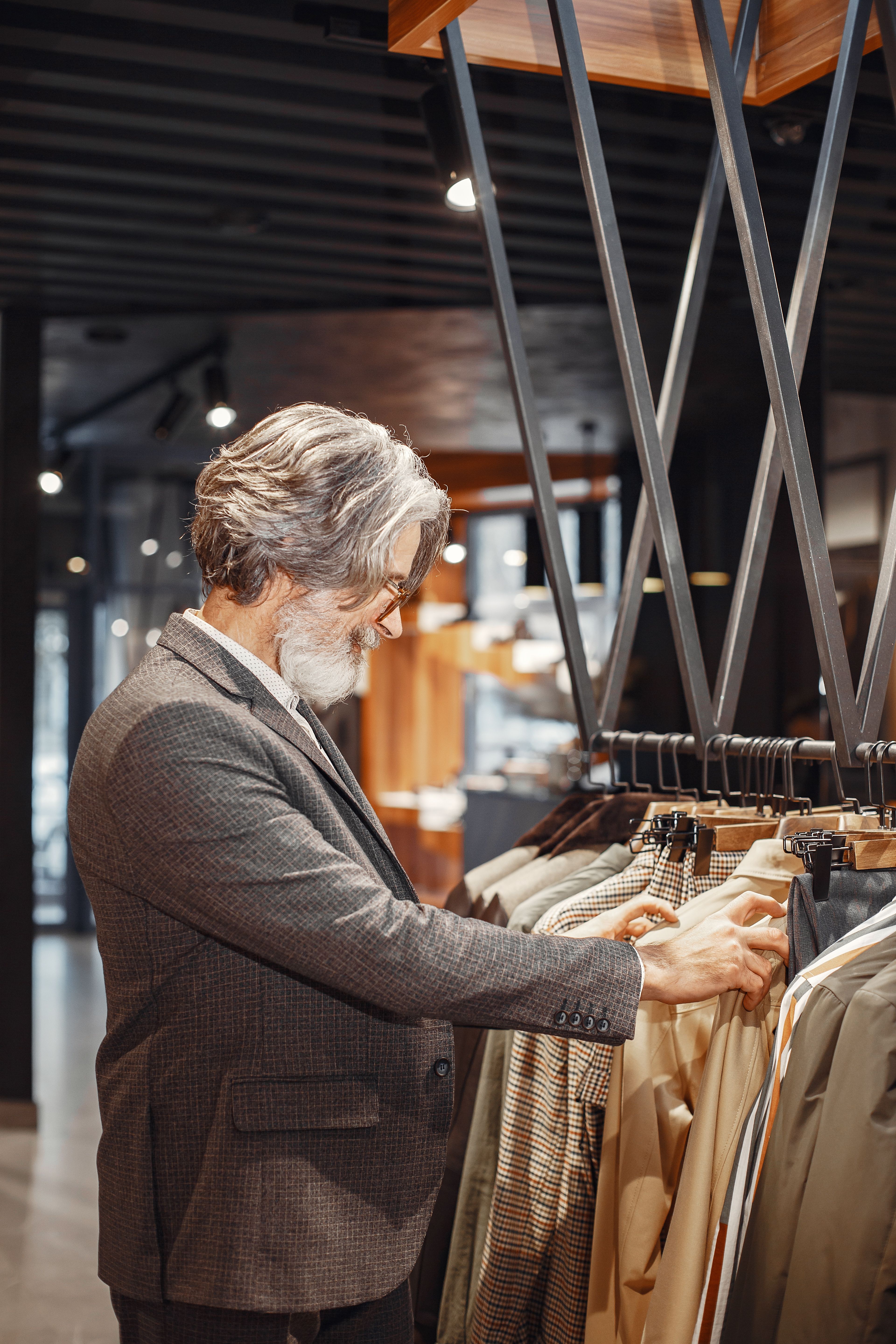 Gentleman prüft Stücke an der Kleiderstange im Store