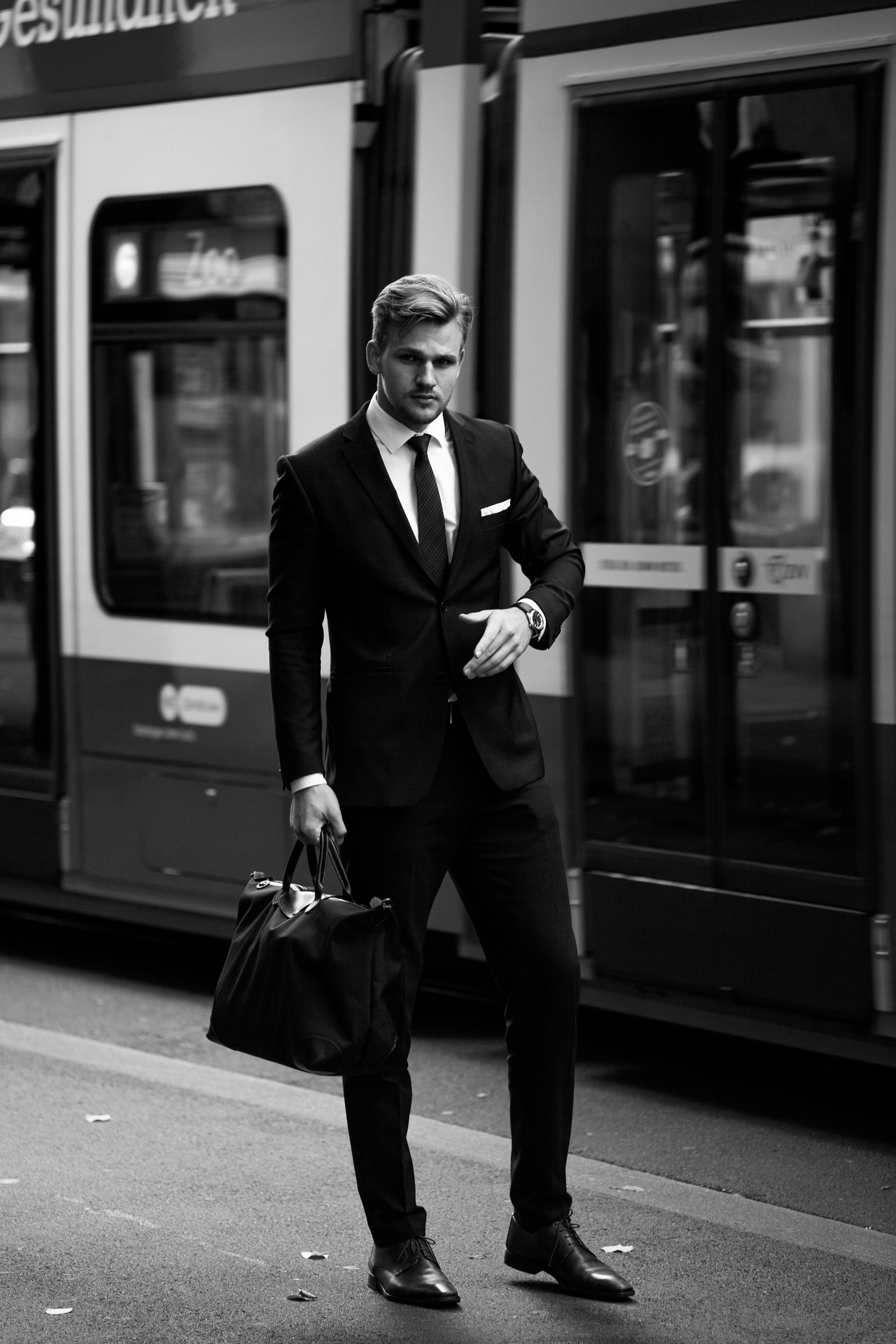 Schwarz-Weiß-Editorial mit Anzug und Reisetasche